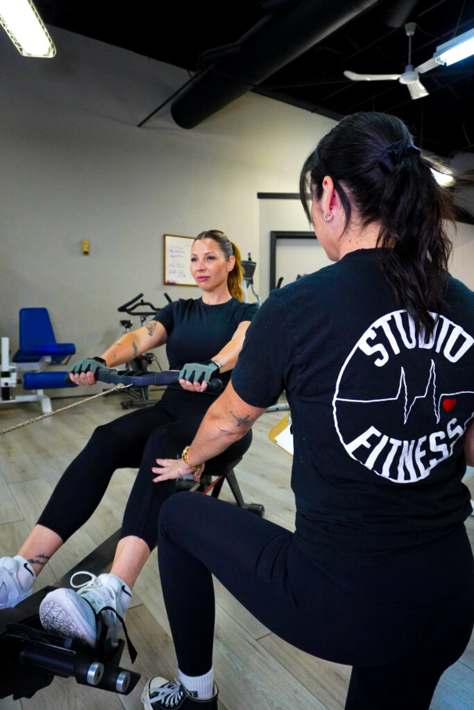 Coach Sophie guide une cliente sur le rameur au Studio Fitness Beauharnois pour un entraînement efficace.